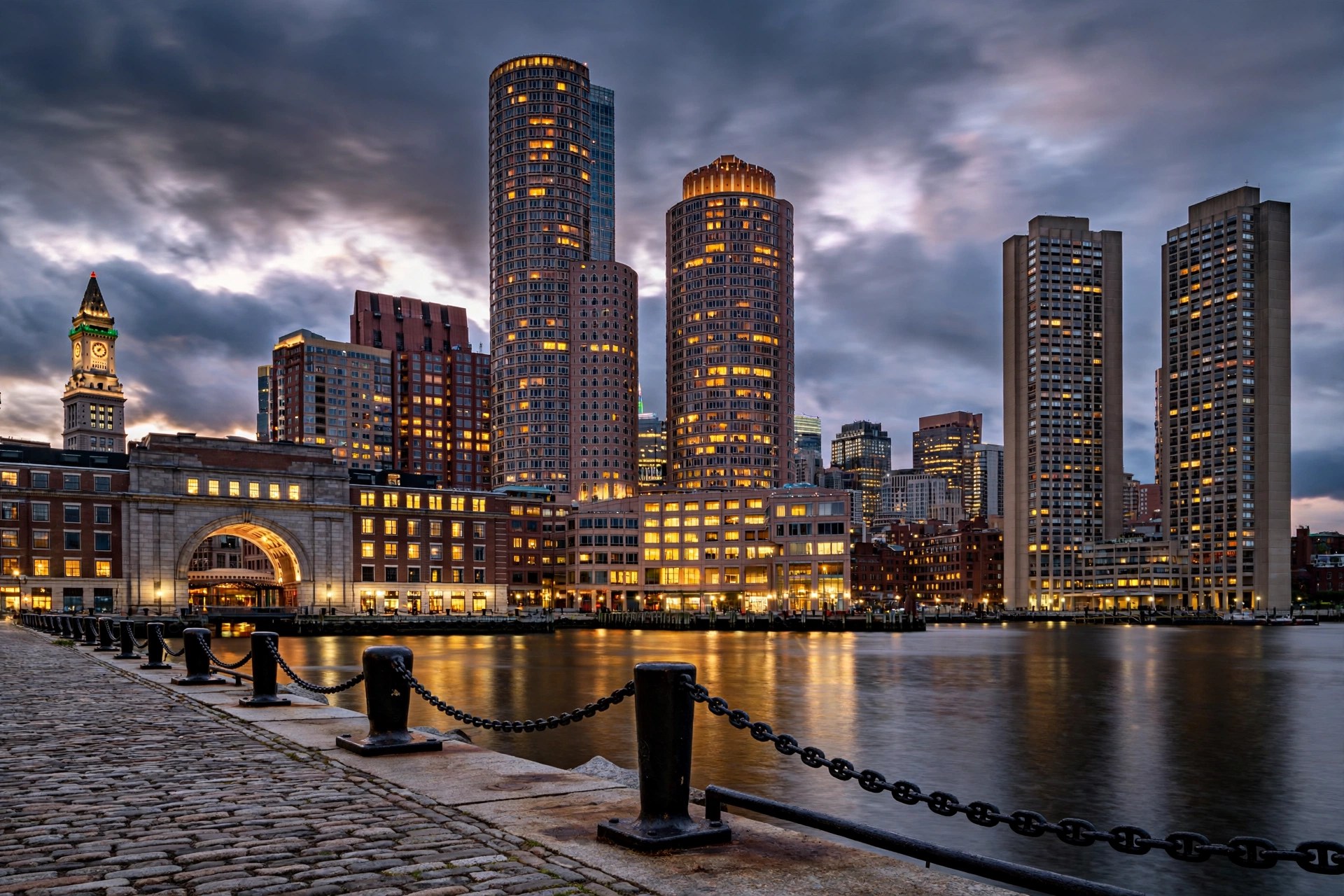 Boston skyline at dusk from Fan Pier, with the Rowes Wharf arch, the Custom House Tower, International Place and the Harbor Towers