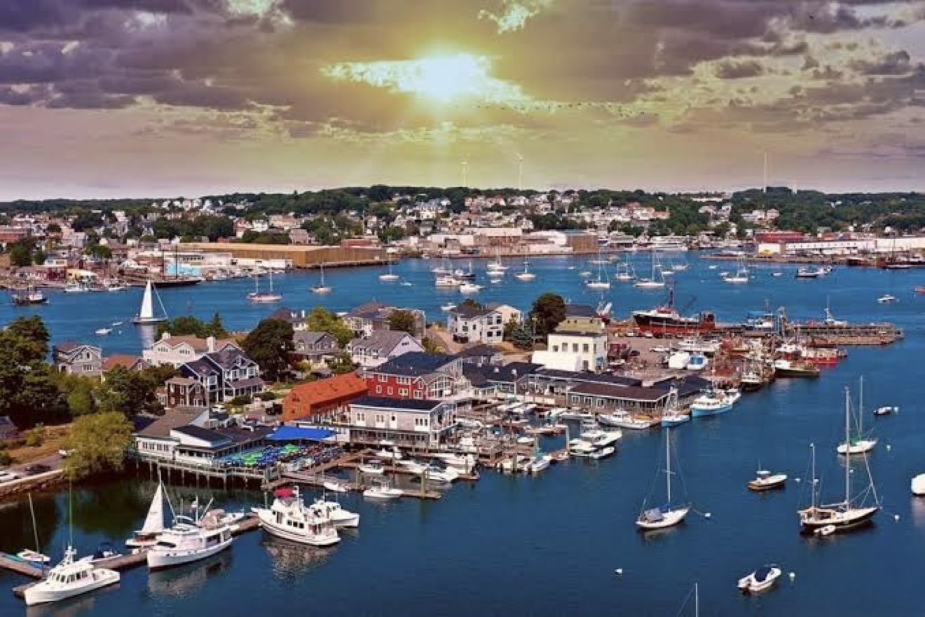 Gloucester Harbor at golden hour, sailboats at mooring along the working waterfront