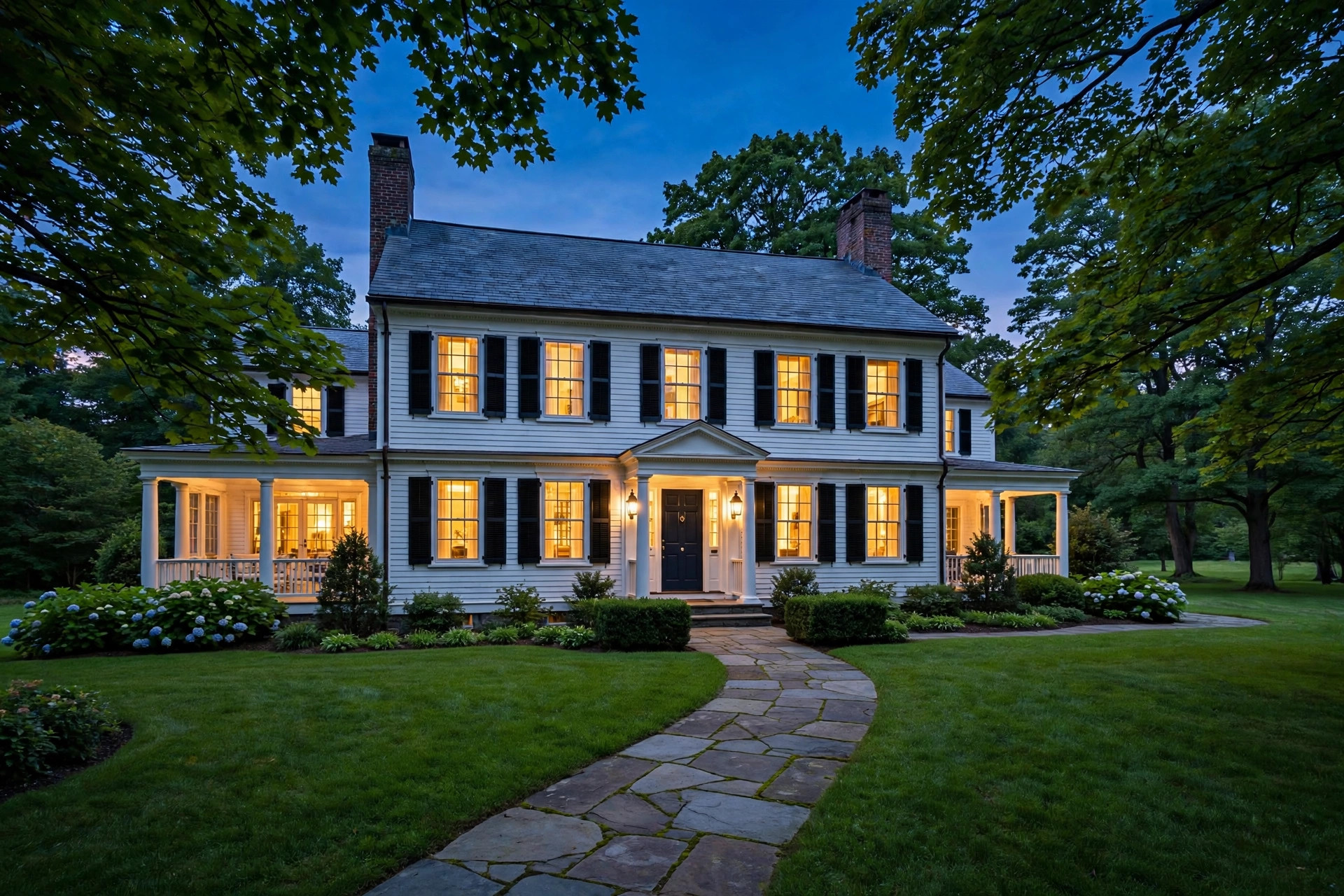 Stately New England colonial home exterior at dusk, warm light glowing in the windows